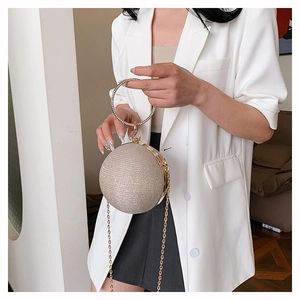 Detail of round champagne evening bag with rhinestone handle and sparkling glitter finish