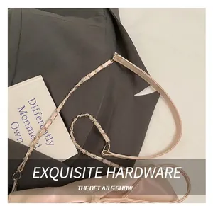 Detail van roze schoudertas met strik en gouden ketting op grijze blazer achtergrond