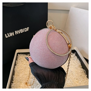 Detail of glitter spherical evening bag with golden circular handles and metal chain