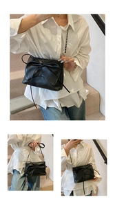 Close-up of black leather shoulder bag with a large bow detail and a fine metal chain strap