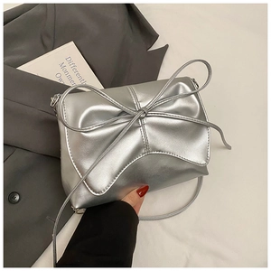 Close-up of metallic silver bow shoulder bag with sleek textured finish and chain strap