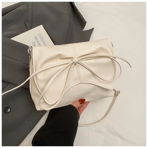 Detail of off-white ruched hobo bag with a large bow and elegant crossbody strap