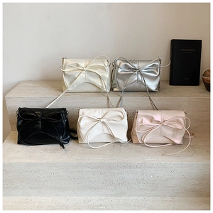 Detail view of ballet-style bow bags in pearl white, silver, black, ivory, and pink