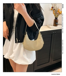 Detailtextur einer hellgoldenen Hobo-Tasche mit feinem gewebtem minimalistischem Muster