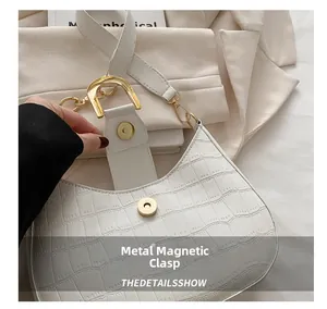 Detail van witte halve maan tas met krokodillenmotief en gouden magneetsluiting