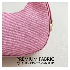 Detailaufnahme der rosa sichelförmigen Tasche mit feiner Webstruktur und Goldzipper