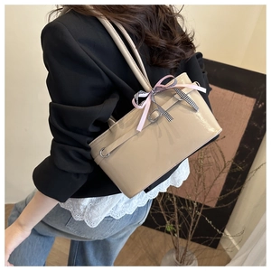 Détail du sac seau en similicuir beige avec ruban rose et nœud à carreaux chic