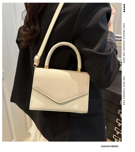Detail of beige quilted flap handbag with golden hardware and adjustable leather strap