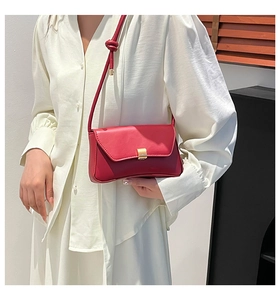 Detail of red square crossbody bag featuring a gold buckle and knotted shoulder strap