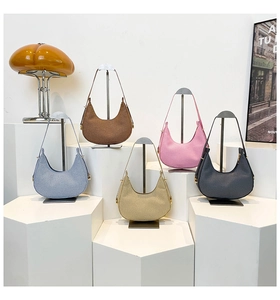 Detailed view of crescent woven shoulder bags displayed in five various colors