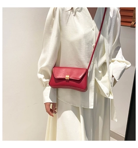 Detail of red leather baguette bag with gold buckle on white vintage shirt outfit