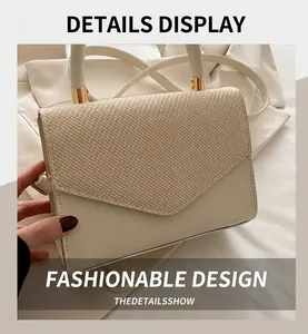 Detail of cream crossbody bag with straw weave texture flap and golden hardware