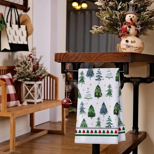 Detail of waffle weave kitchen towel with green Christmas tree patterns hanging on a bar