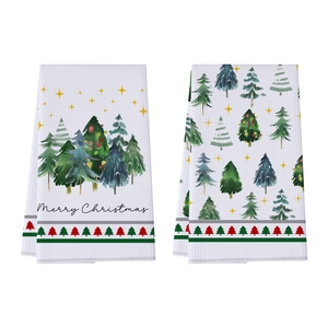 Detail of white waffle kitchen towels with Christmas tree patterns and Merry Christmas text