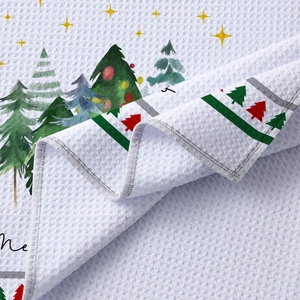 White waffle weave kitchen towel featuring festive Christmas tree and star patterns