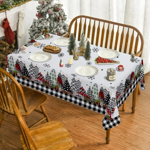 Détail d'une nappe de Noël avec motifs de sapins et bordure à carreaux rouge et noir