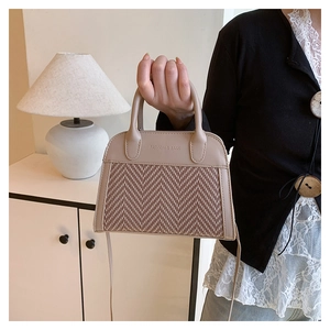Detail of herringbone weave texture and leather trim on beige crossbody pillow bag