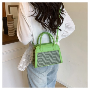 Detail of green leather and herringbone straw stitching on small crossbody handbag