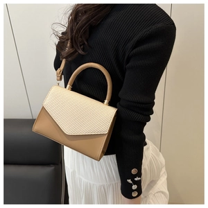 Détails des textures contrastées du cuir kaki et du rabat tissé crème sur le sac