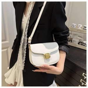 Close-up of a white leather crossbody bag with a gold metal lock worn by a model