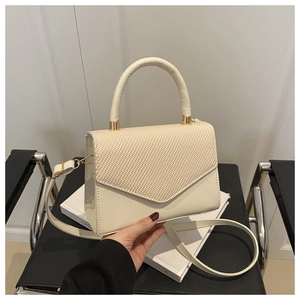 Détail du sac crème avec rabat à texture tressée et finitions métalliques dorées