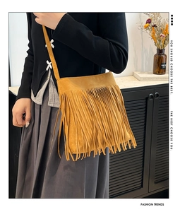 Detail of bohemian ginger yellow suede shoulder bag featuring long fringe tassels
