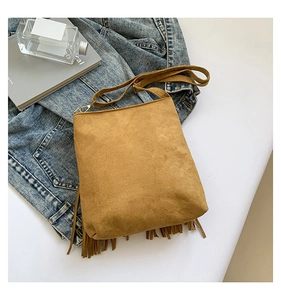 Detail of tan suede shoulder bag with long fringes and elegant gold metal hardware