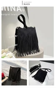 Detail view of black suede shoulder bag featuring long fringe and gold metal buckles