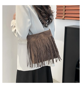 Detailed close-up of dark brown suede shoulder bag featuring long bohemian fringe