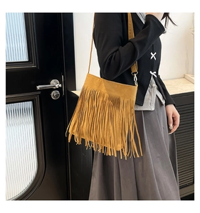 Detail of bohemian ginger yellow suede crossbody bag featuring long stylish tassels