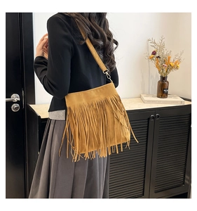 Detail of yellow fringe shoulder bag with long tassels and adjustable strap shown on model