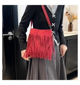 Close-up of red suede shoulder bag featuring bohemian long tassels and shoulder strap