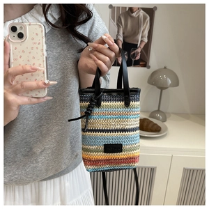 Detail of multi-color woven fiber mini bag with FASHION logo and black round handles