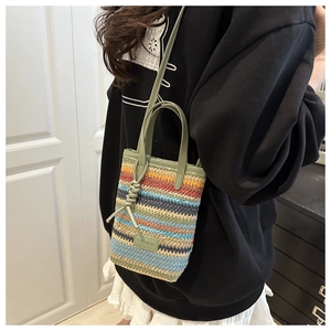 Detailed view of rainbow woven mini bag with green leather handles and fashion tag