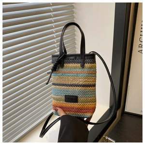 Detail of colorful woven straw bag with black leather handle and Fashion patch label