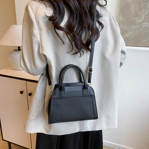 Retro black woven handbag with gold hardware and shoulder strap shown on a model