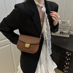 Brown vintage leather saddle bag with gold buckle worn with a black blazer outfit