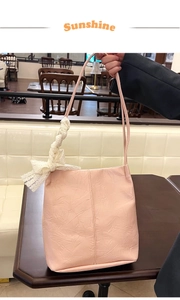 Close-up of pink textured handbag with white lace bow detail on a cafe table