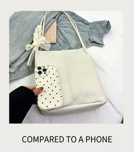 Large white faux leather tote bag with lace bow detail shown next to a smartphone
