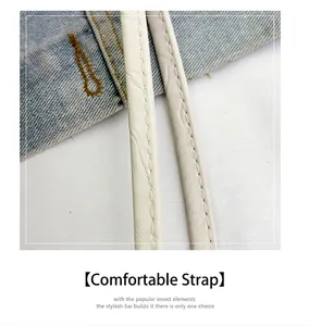 Detail of white leather shoulder strap with precise stitching on denim background