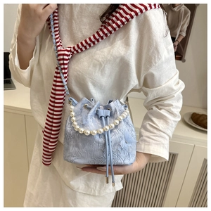 Detail of light blue lace bucket bag with pearl handle and delicate floral embroidery