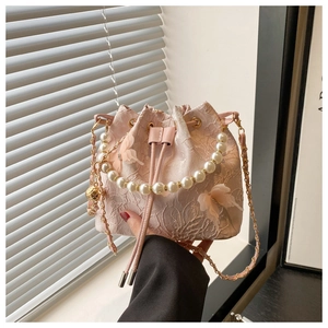 Détail d'un sac seau en dentelle rose avec papillons 3D et poignée en perles élégante