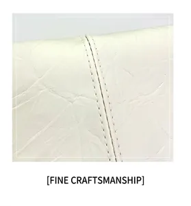 Detailed close-up of white leather texture with reinforced double stitching on the tote bag