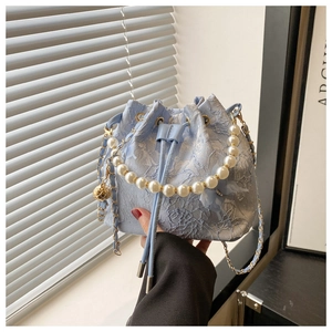 Détail du sac seau en dentelle bleu clair avec poignée en perles et broderies florales
