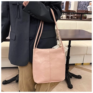 Detailed view of pink pleated shoulder bag featuring a delicate white lace bow charm