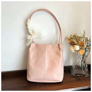Detail of pink pleated tote bag featuring a white lace bow on the shoulder strap