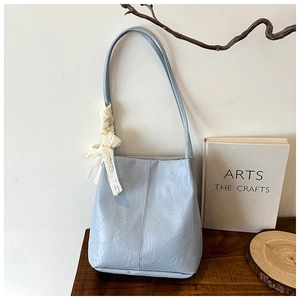 Detail of light blue pleated bucket bag with white lace bow on the shoulder strap