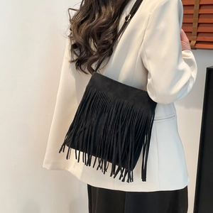 Modern black suede crossbody bag with dense fringe tassel detail worn by a model