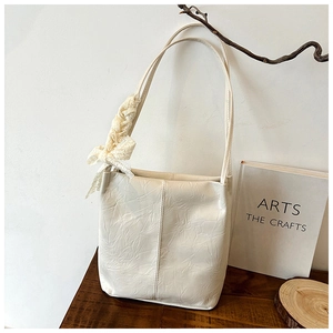 Detail of off-white pleated PU leather tote bag with elegant beige lace bow charm