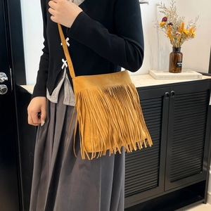Ginger yellow tassel crossbody bag in frosted suede finish worn by model with casual attire
